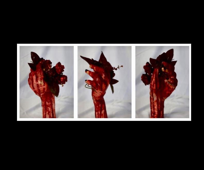 Images from three angles of a sculpture, consisting of a blood-red hand made of clay holding paper roses.